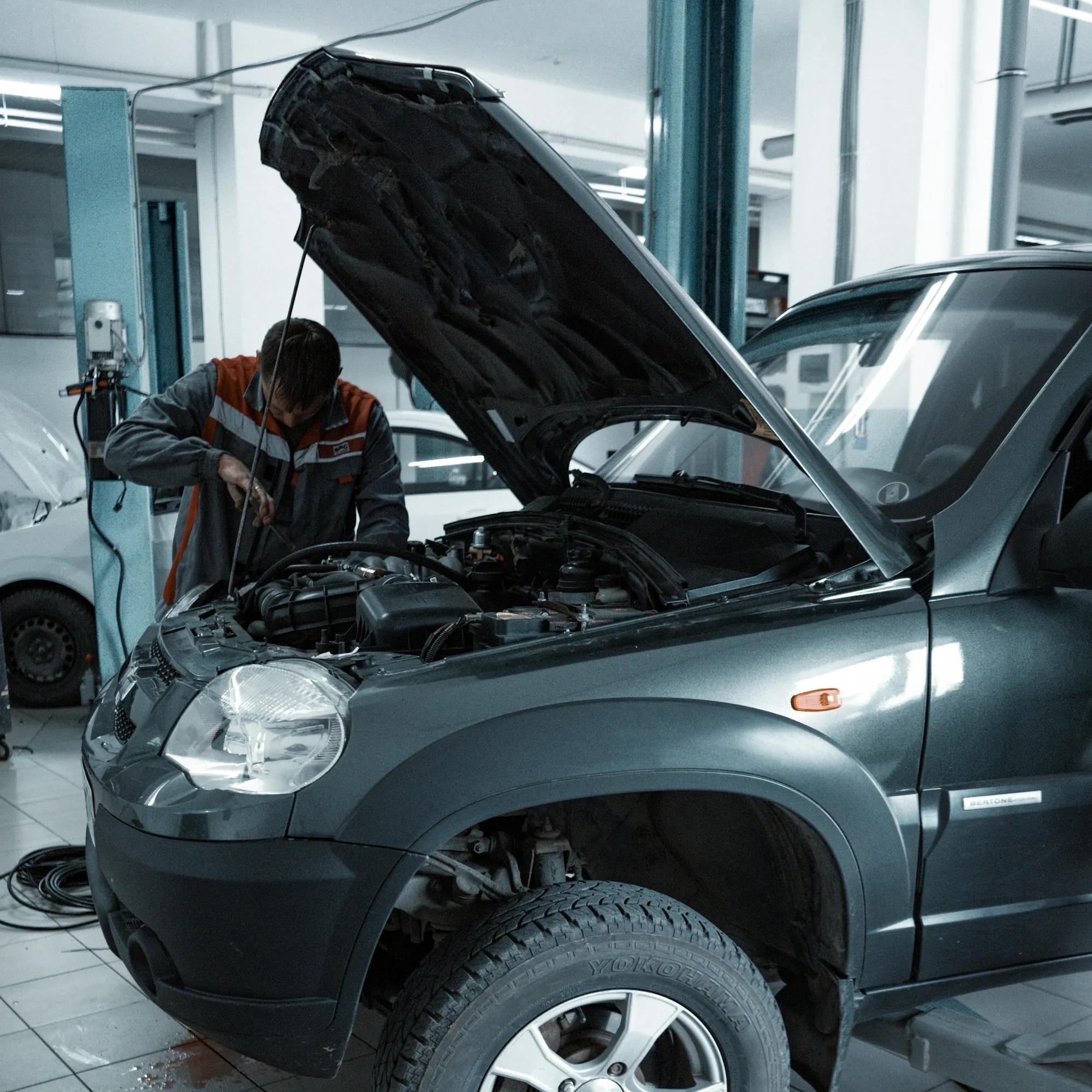 Mechanic leaning into the engine bay of a grey SUV