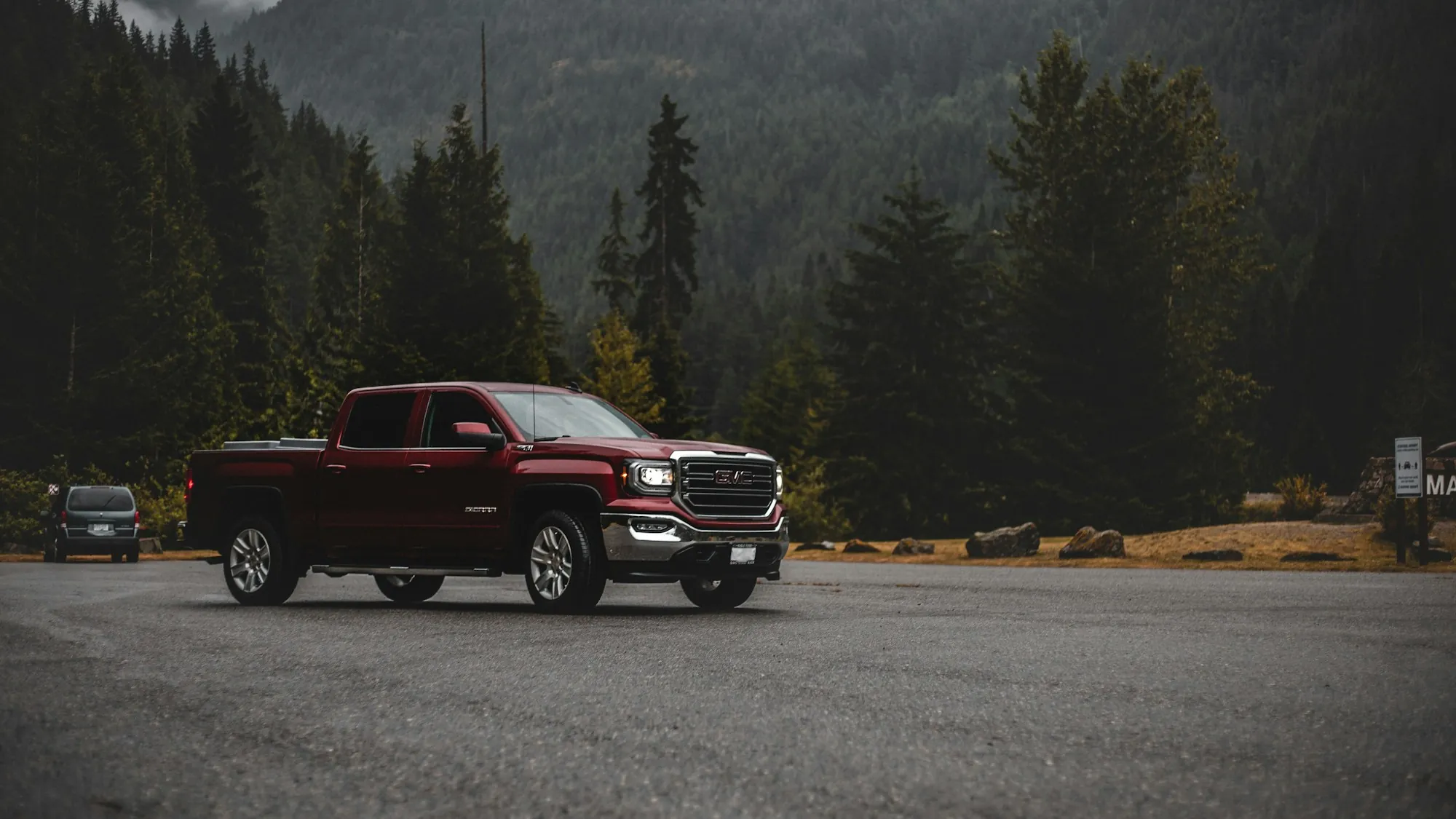 Red pickup on a mountain lot surrounded by pine forest