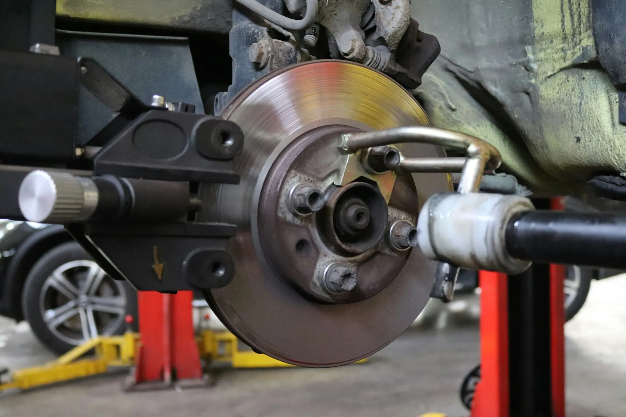 Brake rotor and caliper on a vehicle raised on a shop lift