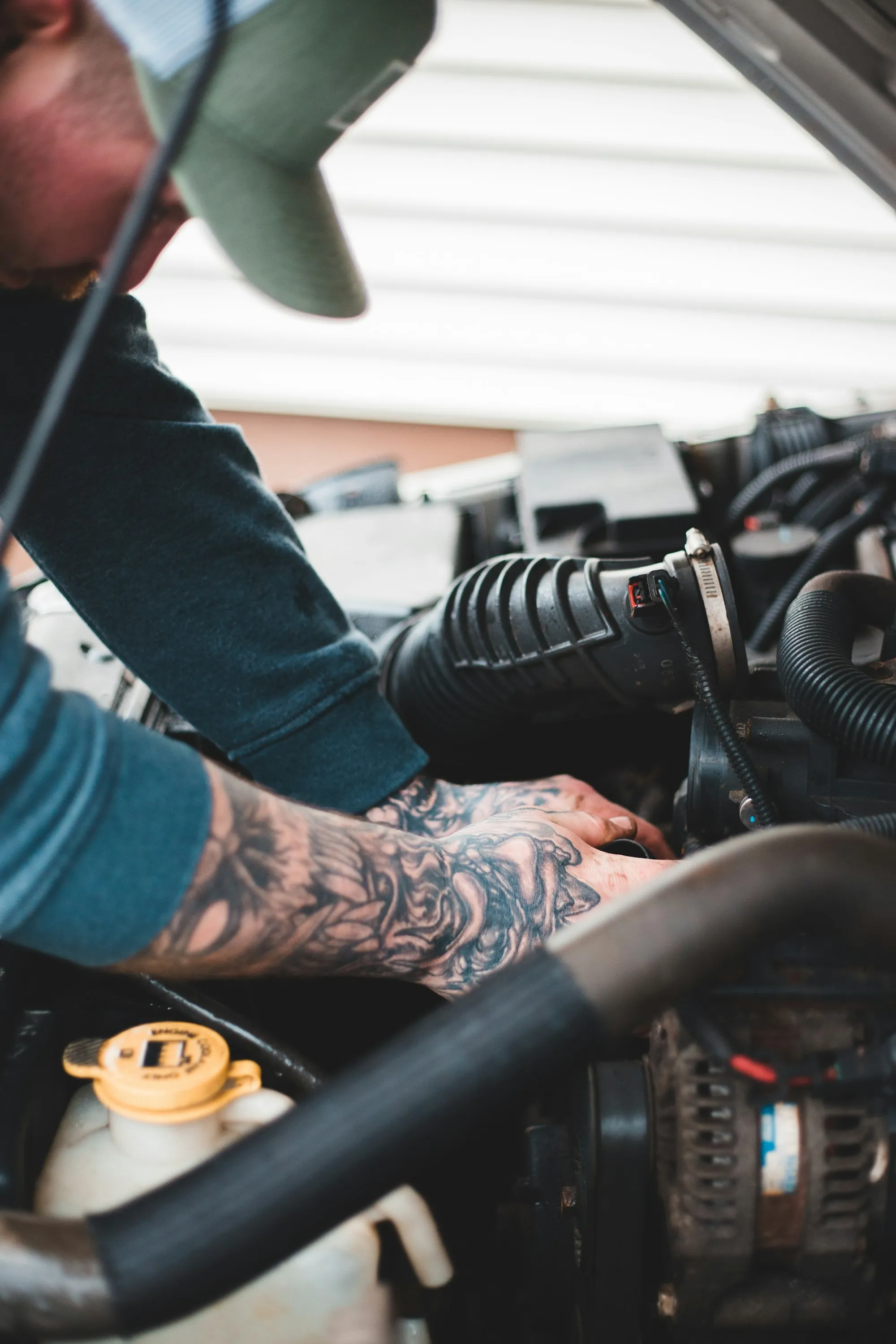 Mechanic with tattooed arms working on an engine bay